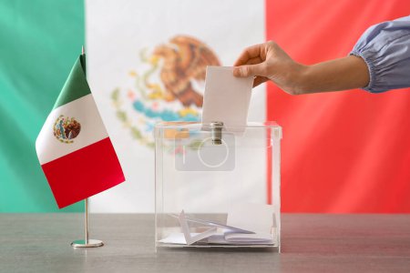 Voting woman with Mexican flag near ballot box on table at polling station
