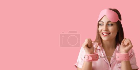 Photo for Young woman in handcuffs from sex shop on pink background with space for text - Royalty Free Image