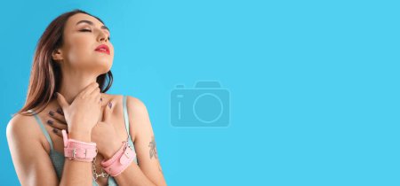 Photo for Beautiful young woman with handcuffs from sex shop on light blue background with space for text - Royalty Free Image