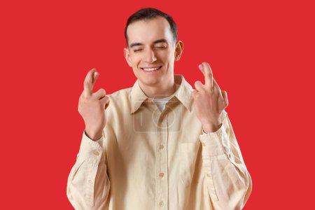 Téléchargez les photos : Jeune homme croisant les doigts sur fond rouge - en image libre de droit
