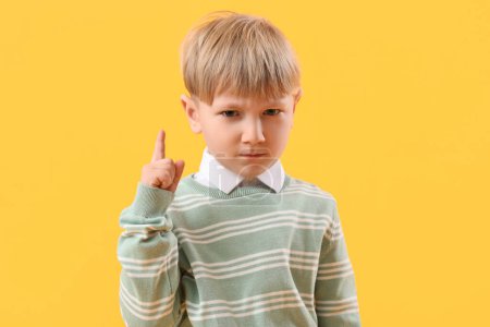 Funny little businessman pointing at something on yellow background