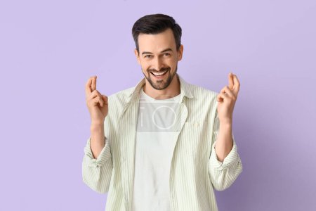 Foto de Hombre guapo cruzando los dedos sobre fondo lila - Imagen libre de derechos