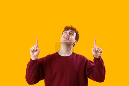 Photo for Young redhead man pointing at something on yellow background - Royalty Free Image