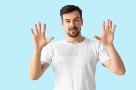 Photo for Handsome man showing hands on blue background - Royalty Free Image