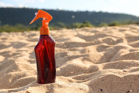 Botella de crema protector solar sobre arena en la playa