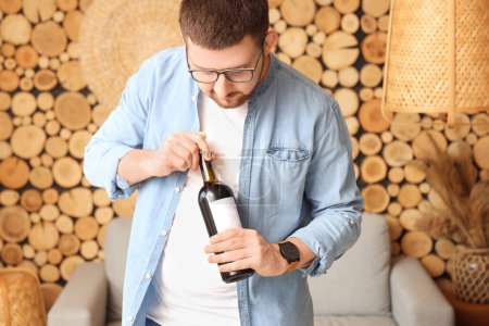 Photo for Sommelier opening bottle of wine with corkscrew in living room - Royalty Free Image