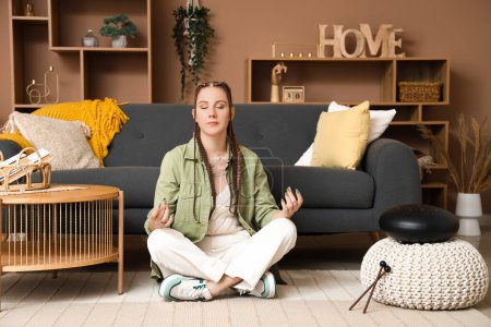 Young woman with glucophone meditating at home