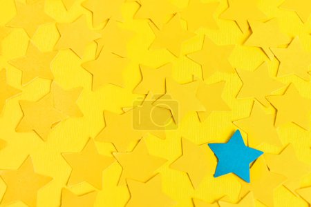 Téléchargez les photos : Une étoile bleue parmi les jaunes sur fond de couleur. Concept d'unicité - en image libre de droit