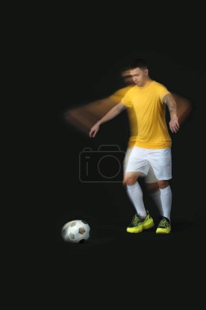 Deportivo joven jugando con pelota de fútbol en movimiento sobre fondo oscuro