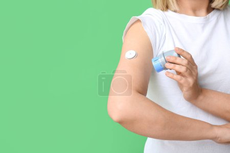 Frau mit Glukosesensor zur Messung des Blutzuckerspiegels und Applikator auf grünem Hintergrund. Diabetes-Konzept