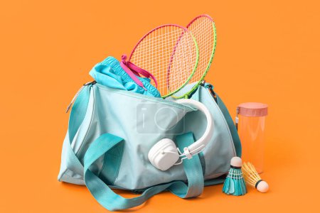 Téléchargez les photos : Sac de sport, raquettes de badminton, écouteurs et bouteille d'eau sur fond orange - en image libre de droit