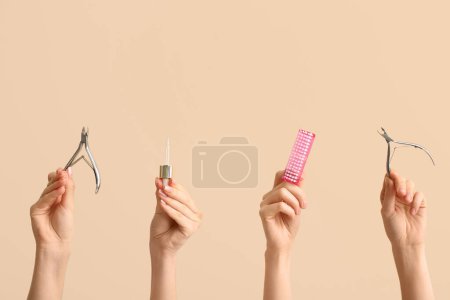 Female hands with pipette for cuticle oil, nail cutters and brush on beige background