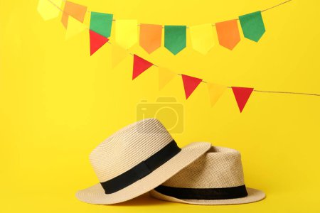 Téléchargez les photos : Chapeaux de paille avec des drapeaux sur fond jaune. Fête Junina (Festival de juin) - en image libre de droit