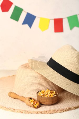 Téléchargez les photos : Cuillère avec bol de maïs et chapeaux de paille sur la table blanche. Fête Junina (Festival de juin) - en image libre de droit
