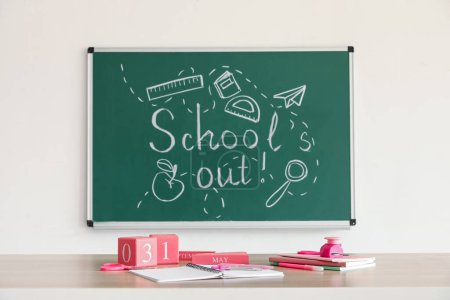 Photo for Blackboard with text SCHOOL'S OUT, drawings and desk in classroom - Royalty Free Image