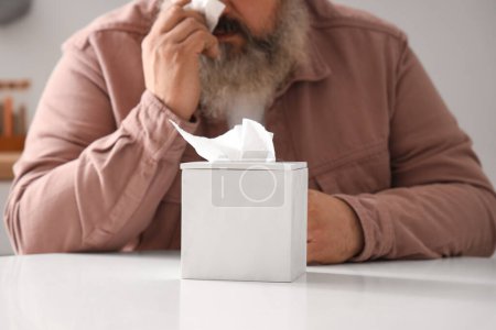 Photo for Portrait of sad senior man with tissues sitting at table in kitchen - Royalty Free Image