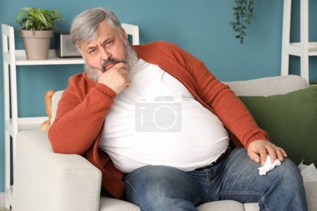 Porträt eines traurigen älteren Mannes mit Taschentüchern, der auf dem Sofa im Wohnzimmer sitzt
