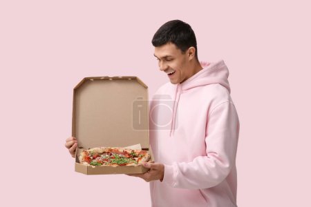 Photo for Young man holding cardboard box with tasty pizza on pink background - Royalty Free Image
