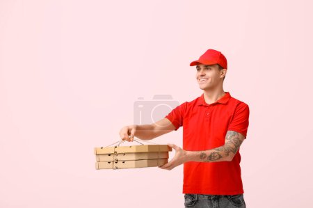 Photo for Delivery man holding cardboard boxes with tasty pizza on pink background - Royalty Free Image