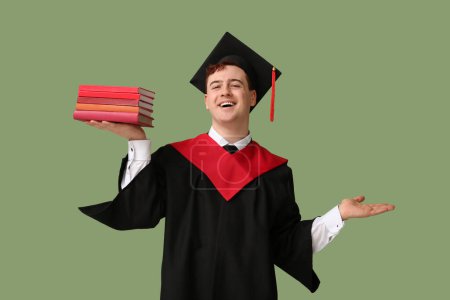Photo for Male graduating student with books on green background - Royalty Free Image