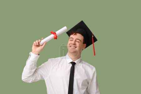 Photo for Male student in mortar board with diploma on green background - Royalty Free Image
