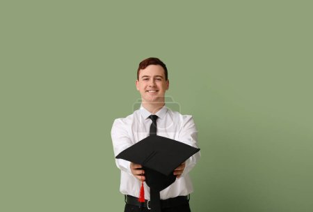 Photo for Male student with mortar board on green background - Royalty Free Image