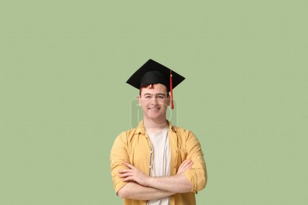 Photo for Happy male student in mortar board on green background - Royalty Free Image