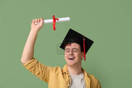 Photo for Happy student in mortar board with diploma on green background - Royalty Free Image