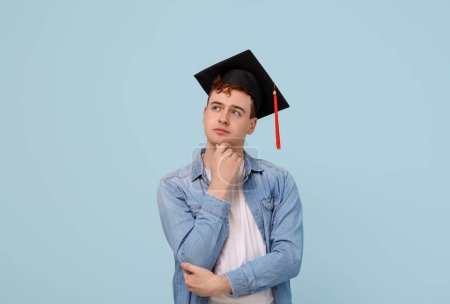 Photo for Thoughtful male student in mortar board on blue background - Royalty Free Image