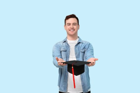 Photo for Male student with mortar board on blue background - Royalty Free Image