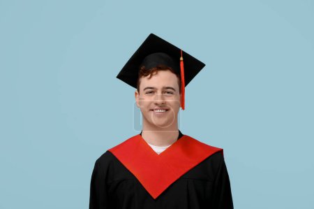 Photo for Happy male graduating student on blue background - Royalty Free Image