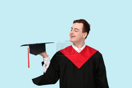 Photo for Male graduating student holding mortar board on blue background - Royalty Free Image