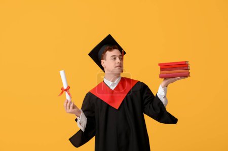 Photo for Male graduating student with diploma and books on yellow background - Royalty Free Image