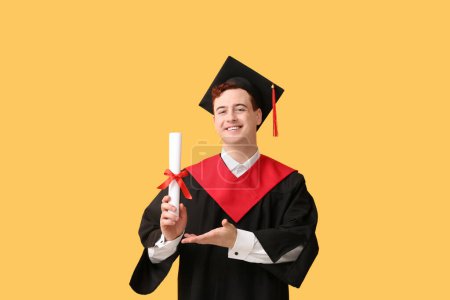 Photo for Male graduating student with diploma on yellow background - Royalty Free Image