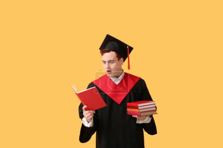 Photo for Shocked graduating student with books on yellow background - Royalty Free Image