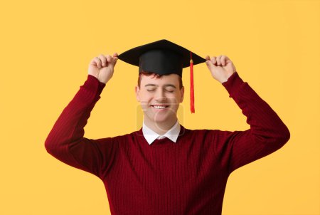Photo for Happy male student in mortar board on yellow background - Royalty Free Image