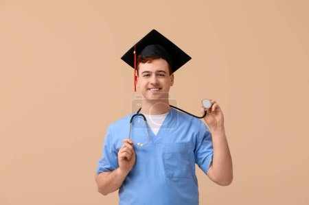 Photo for Male student in mortar board and uniform of doctor on beige background - Royalty Free Image