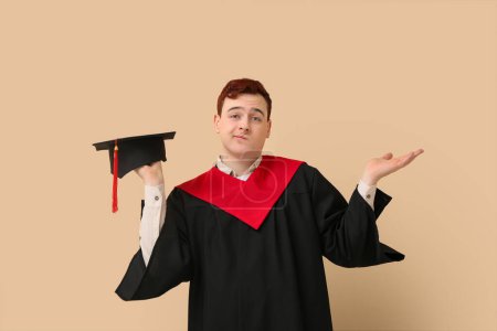 Photo for Male graduating student with mortar board on beige background - Royalty Free Image