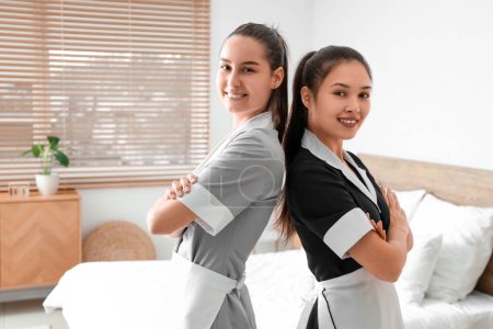 Young chambermaids smiling in bedroom