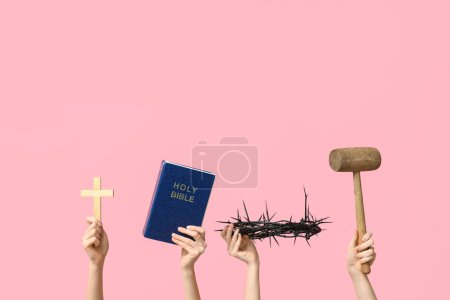 Frauenhände mit Bibel, Dornenkrone, Kreuz und Schlägel auf rosa Hintergrund. Karfreitagskonzept