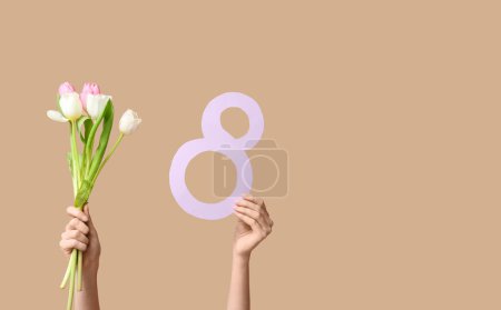 Manos femeninas con figura de papel 8 y hermosas flores de tulipán sobre fondo de color. Día Internacional de la Mujer