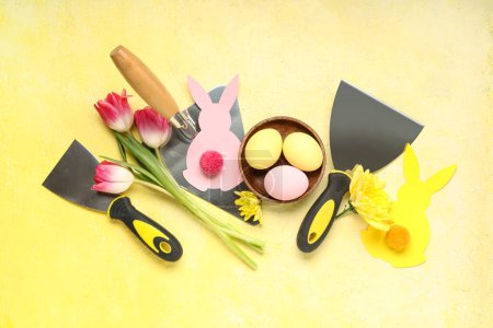 Komposition mit Ostereiern, Blumen und Baukellen auf farbigem Hintergrund