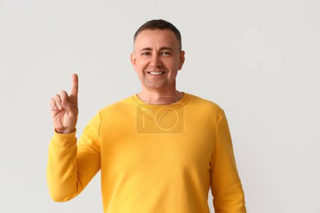 Photo for Mature man pointing at something on light background - Royalty Free Image