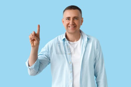 Photo for Mature man pointing at something on blue background - Royalty Free Image