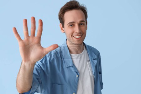 Photo for Young man showing hand on blue background, closeup - Royalty Free Image