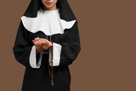 Praying young nun on brown background