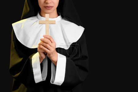 Young nun with cross on black background