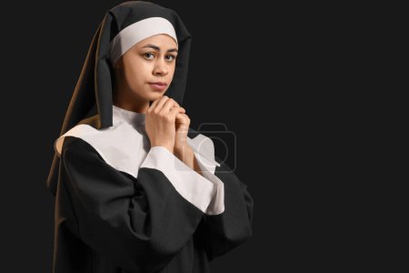 Young nun on black background