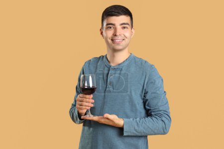 Téléchargez les photos : Jeune homme avec un verre de vin rouge sur fond beige - en image libre de droit