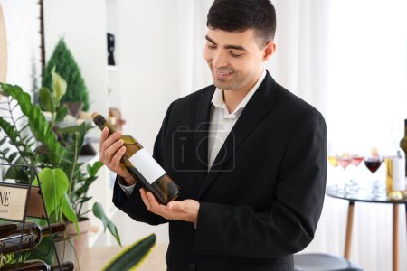 Photo for Young sommelier with bottle of wine in kitchen - Royalty Free Image
